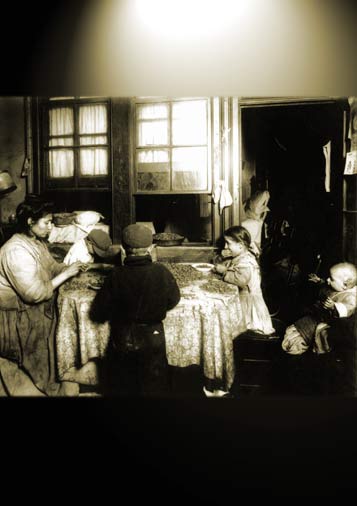 Photo of a working family of five -- three of the older kids who are sitting around a dining table with their mother and baby sibling, taken in the US in the early 20th century.