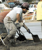 Laborer shoveling concrete