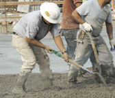 Laborer sliding concrete with a shovel