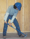Carpenter bending over to pound nails