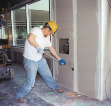Carpenter reaching out and overhead while using a drill 