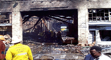 firefighters inspecting a burnt out building.