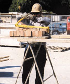 Laborer lifting bricks with brick tongs