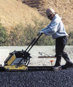 Laborer using a compactor on asphalt