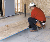 Laborer squatting to grasp plywood