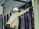 Carpenter reaching out and overhead while using a drill 