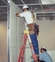 Two carpenters working together, one on the floor, the other on a ladder