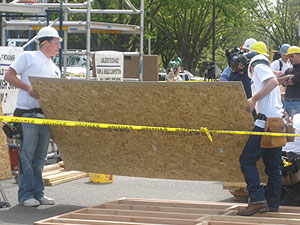 2 people carrying large wooden board